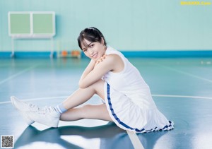 A woman in a white shirt and skirt standing on a tennis court.