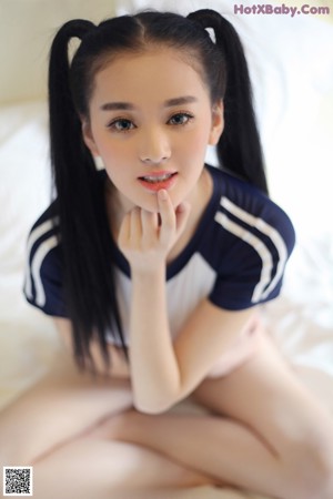 A woman sitting on top of a bed with her legs crossed.