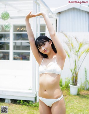 A woman in a white bikini sitting on the ground.