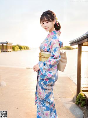 A woman in a blue kimono and a straw hat on a beach.