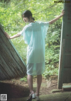 A woman standing in front of a pile of hay.