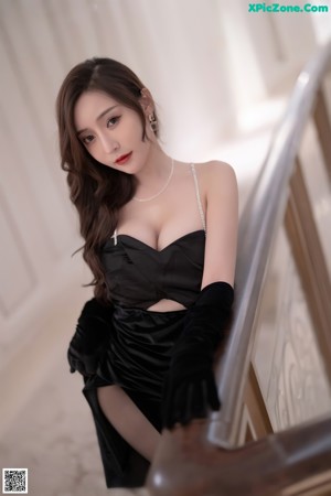 A woman in a black dress and high heels posing for a picture.