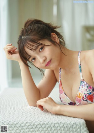A woman in a bikini sitting on a window sill.