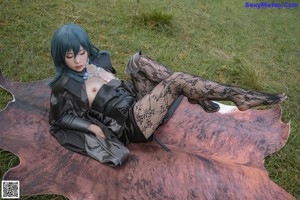 A woman with blue hair is posing in a black outfit.