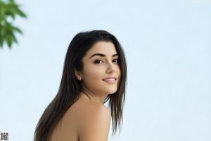 A naked woman sitting on top of a white couch.