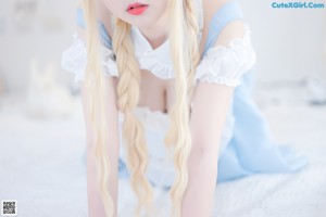 A woman in a blue dress and white stockings laying on a bed.