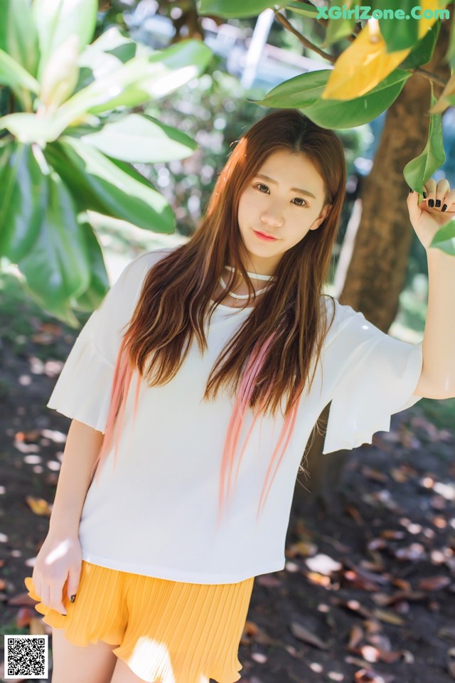 A woman in a white shirt and yellow skirt posing for a picture.