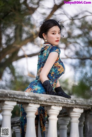 A woman in a green dress and black gloves posing for a picture.