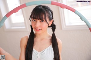 A young girl in a white leotard and blue skirt holding a hoop.