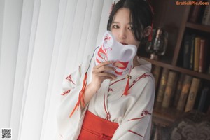 A woman in a white and red kimono sitting on a couch.