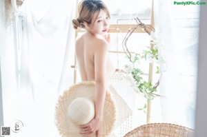 A woman in a blue bikini sitting on a wicker chair.