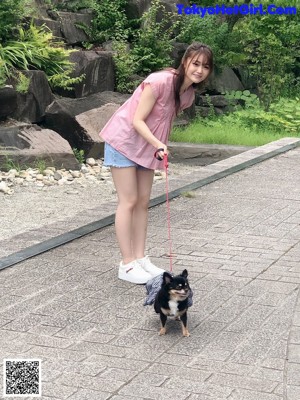 A young girl holding a small dog on a leash.