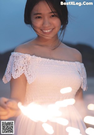 A woman wrapped up in a towel on the beach.