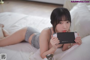 A woman laying on a bed holding a cell phone.