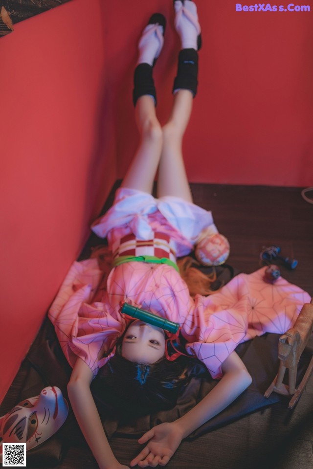 A woman in a pink kimono laying on the floor.