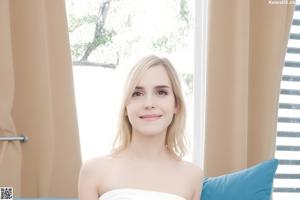 A woman sitting on top of a bed in a room.