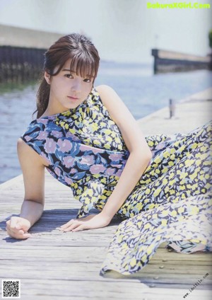 A woman standing on a dock next to a body of water.