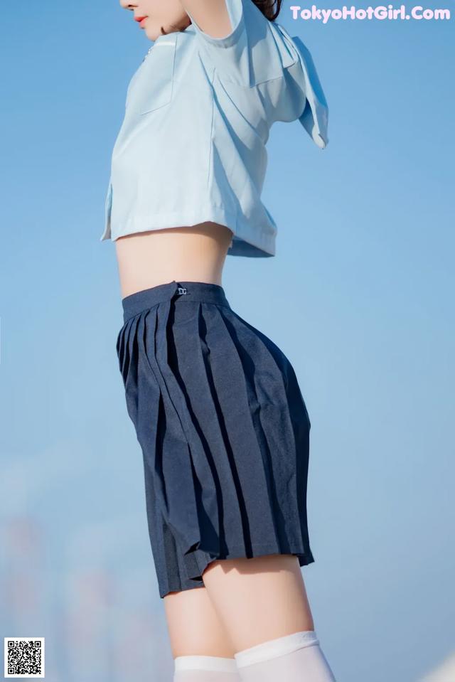 A woman in a blue shirt and skirt posing for a picture.