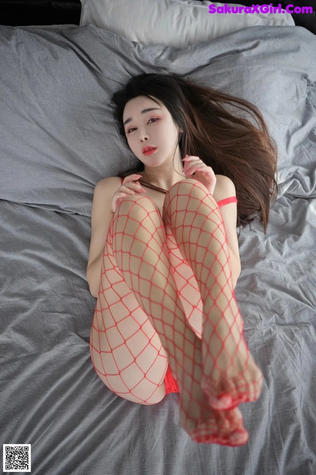 A woman in fishnet stockings laying on a bed.