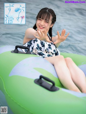 A young girl in a blue dress is sliding down a water slide.