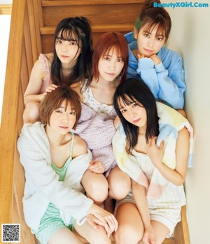 A group of young women sitting on top of a wooden staircase.