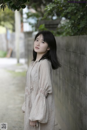 A woman in a beige dress sitting on a dirt road.