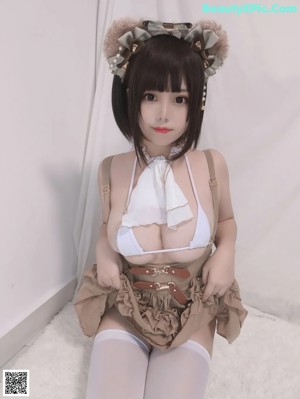 A woman in a white bra top and white tights sitting on a white rug.