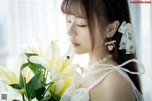 A woman in a white dress holding a bunch of white flowers.