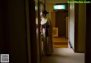 A woman in a kimono sitting on a couch in a room.