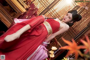 A woman in a red dress sitting on a bed.