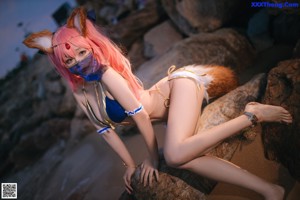 A woman in a bikini sitting on a log on the beach.