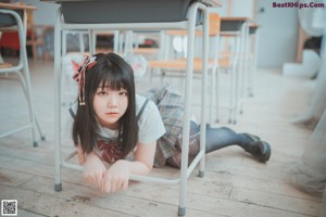 A girl in a school uniform sitting on a bench.