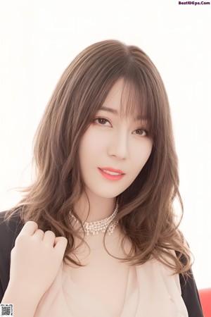 A woman with long brown hair wearing a pink shirt.