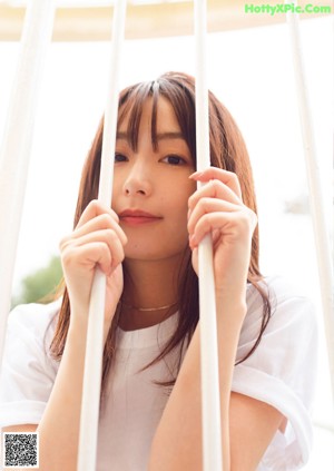 A woman standing next to a red railing holding a piece of food.