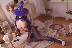 A woman in a witch costume is posing on a bed.